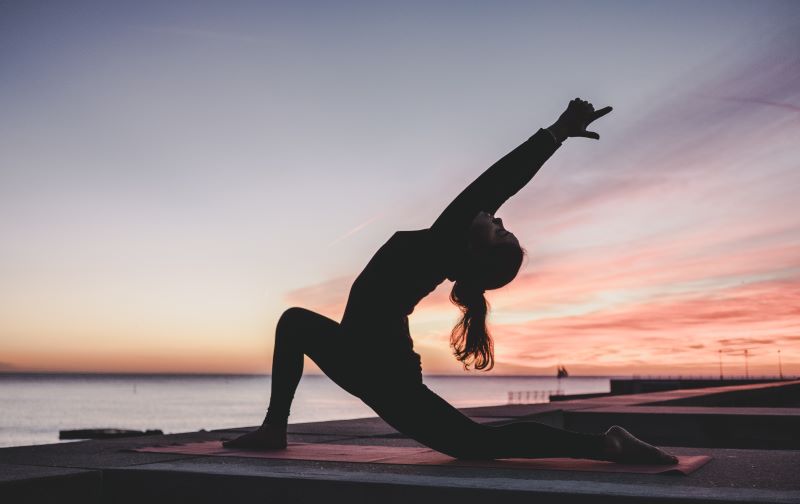 Traveler practicing yoga at DFW airport yoga spaces in Terminal D while overlooking the runway.